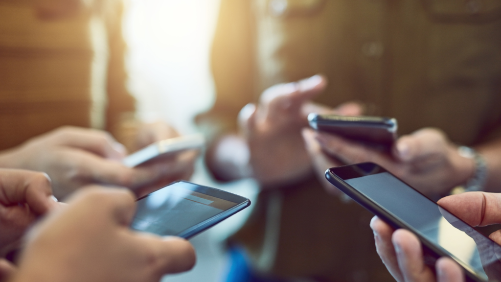 Several people holding and using their smartphones, with only their hands and devices visible.